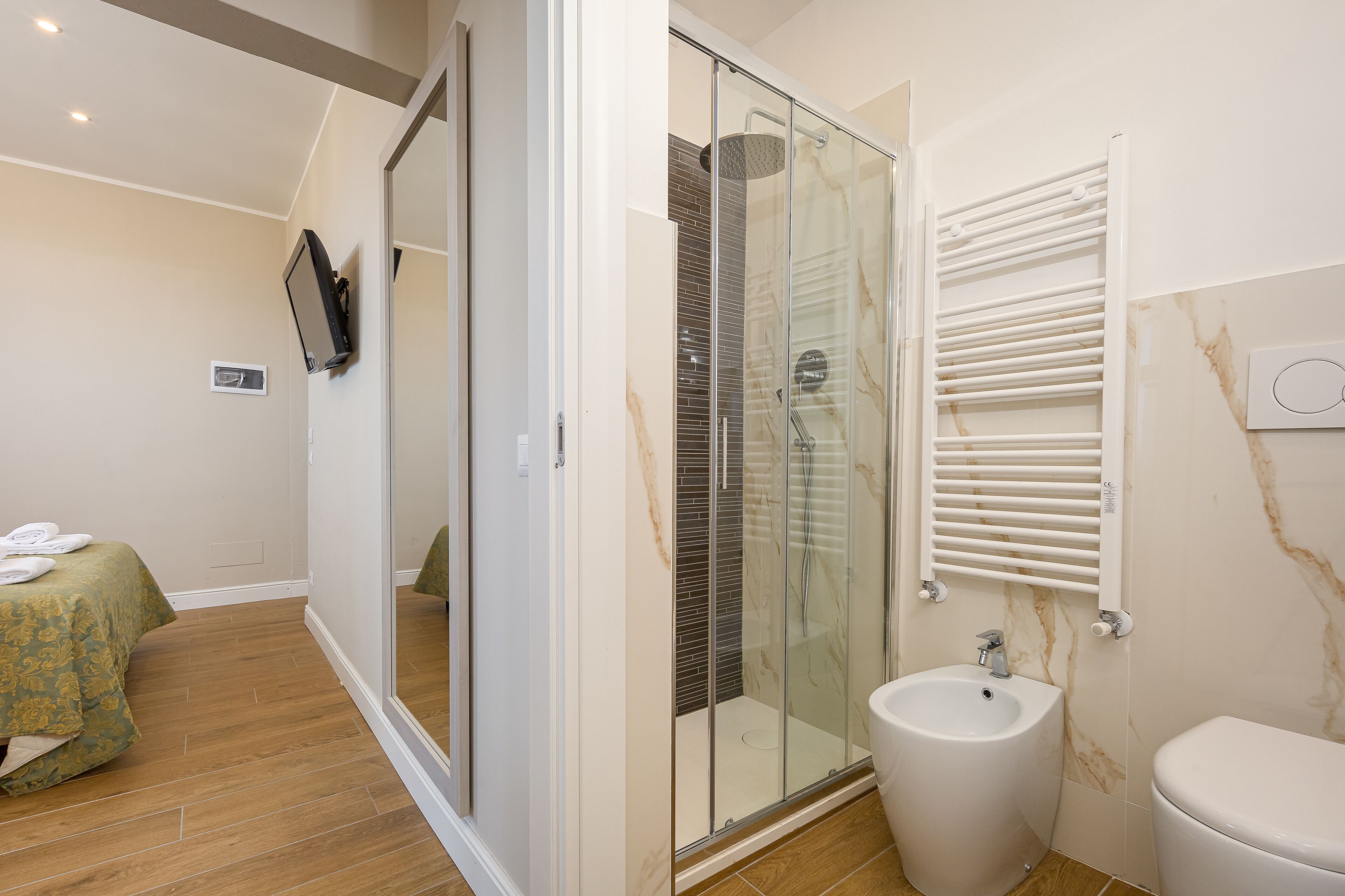 A modern bathroom with a glass shower enclosure, a bidet, and a toilet.
