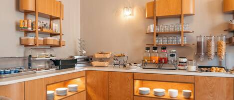 Una cocina moderna con armarios de madera, una estación de café y diversos alimentos.