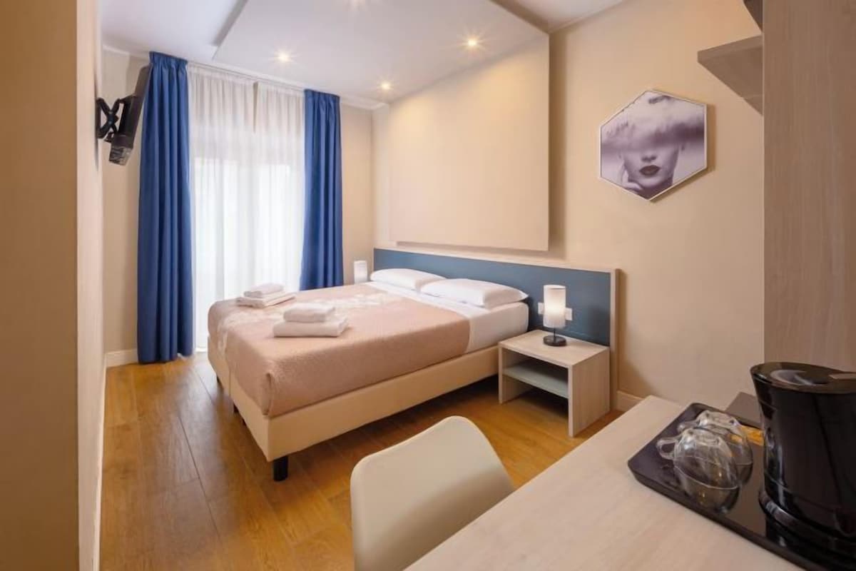 Een hotelkamer met een bed, nachtkastje, stoel en koffiezetapparaat.