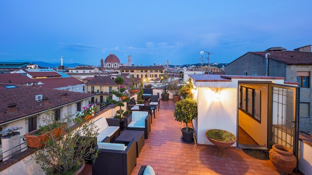 A rooftop terrace with outdoor seating, potted plants, and a view of the cityscape. - Hotel Bijou Roof Terrace (Florence)