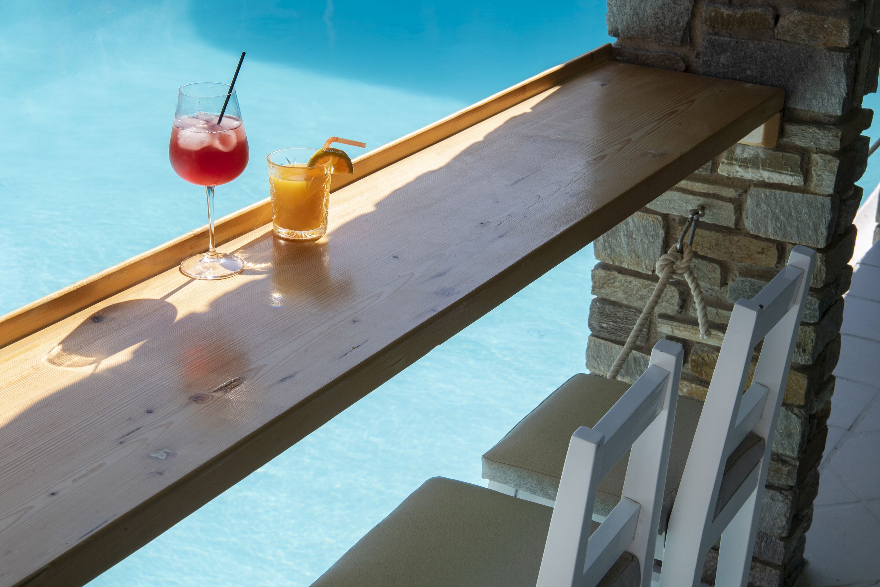 A wooden tray with drinks by a poolside.