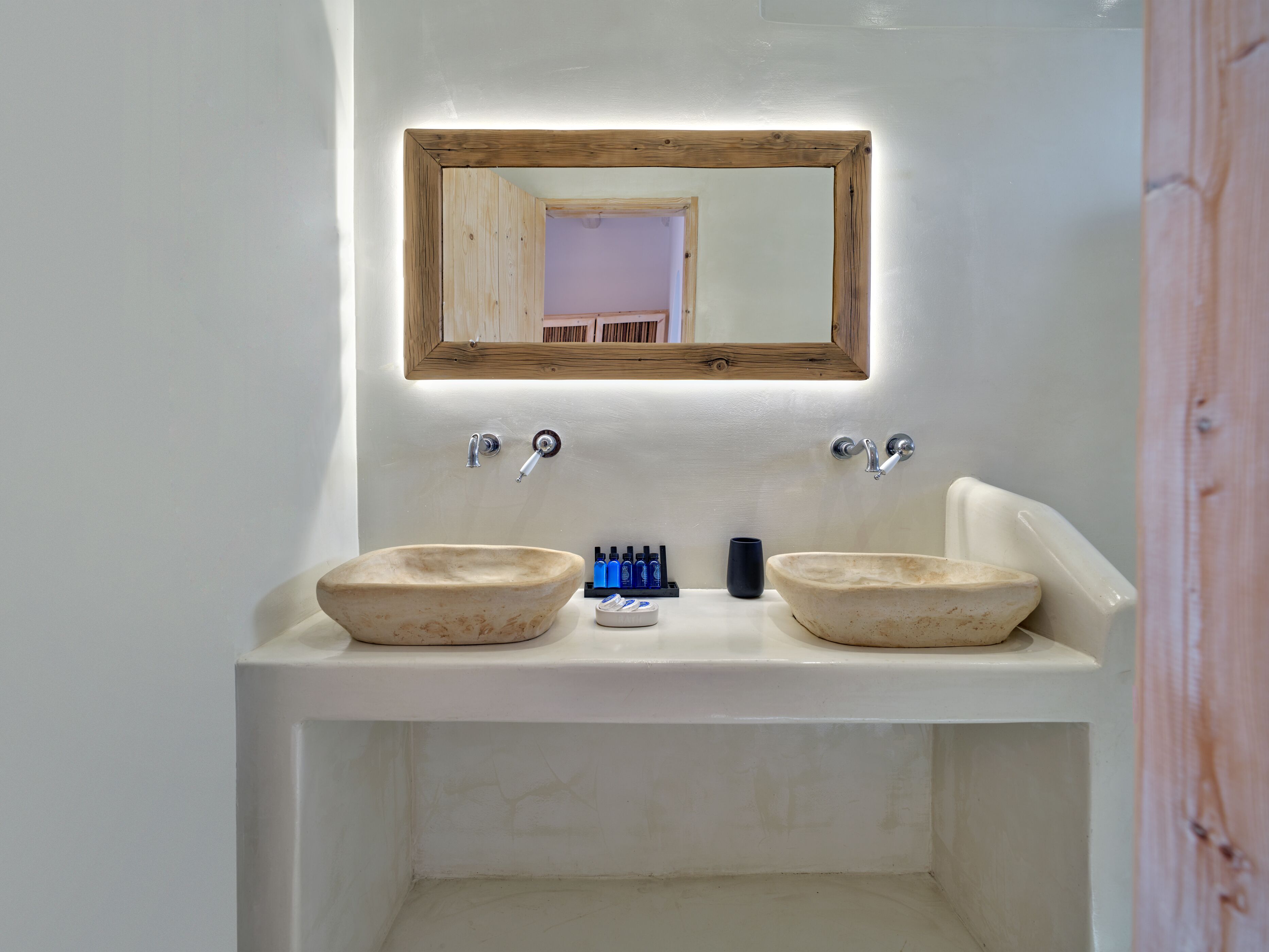 A bathroom with a double sink, a mirror, and a wooden frame.