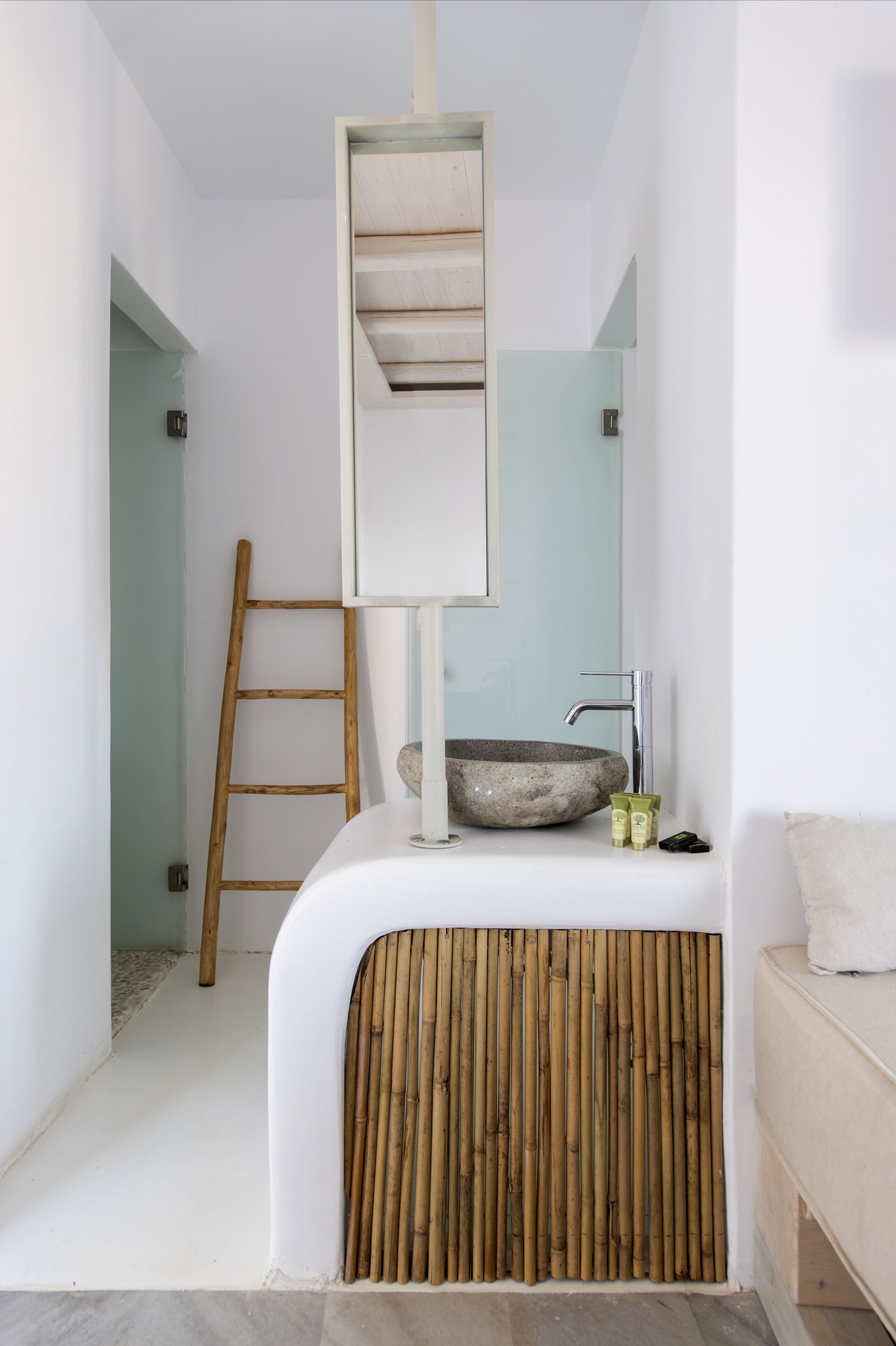 A bathroom with a white sink, a wooden ladder, and a bamboo panel.