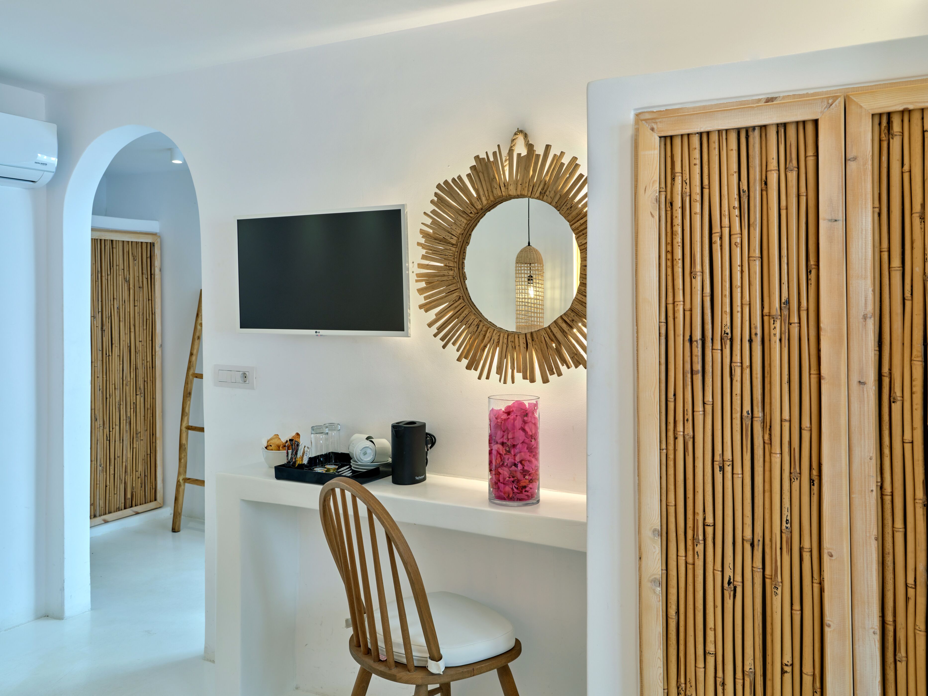 Une chambre moderne équipée d’une télévision, d’un miroir décoratif, d’une chaise en bois et d’une étagère contenant divers objets.