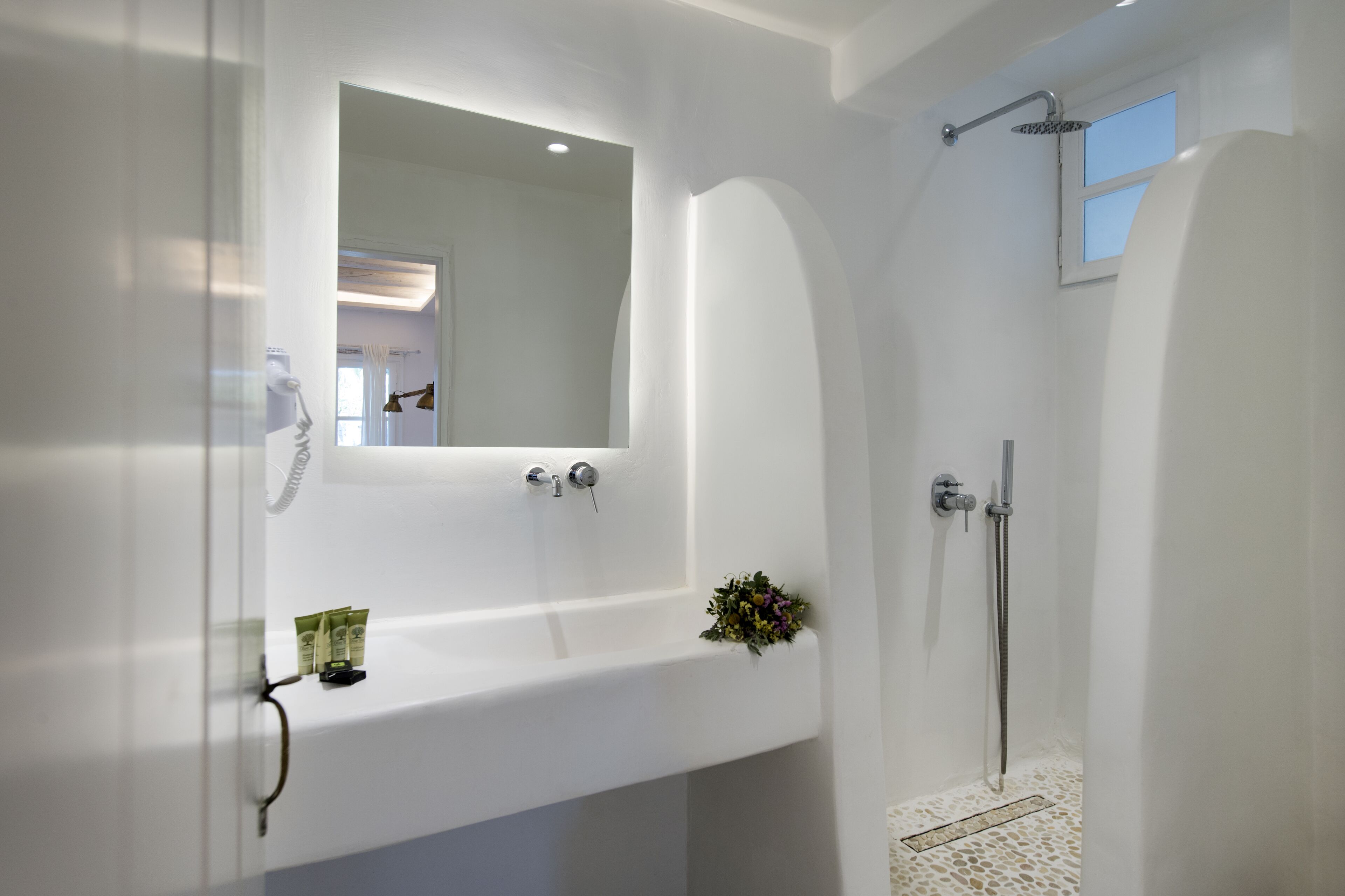 Un baño moderno con un lavamanos blanco, un espejo y una ducha.