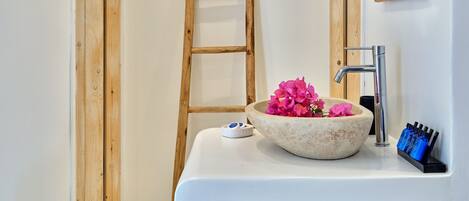 A bathroom with a wooden ladder, a white sink with a stone basin, and two wooden-framed mirrors.