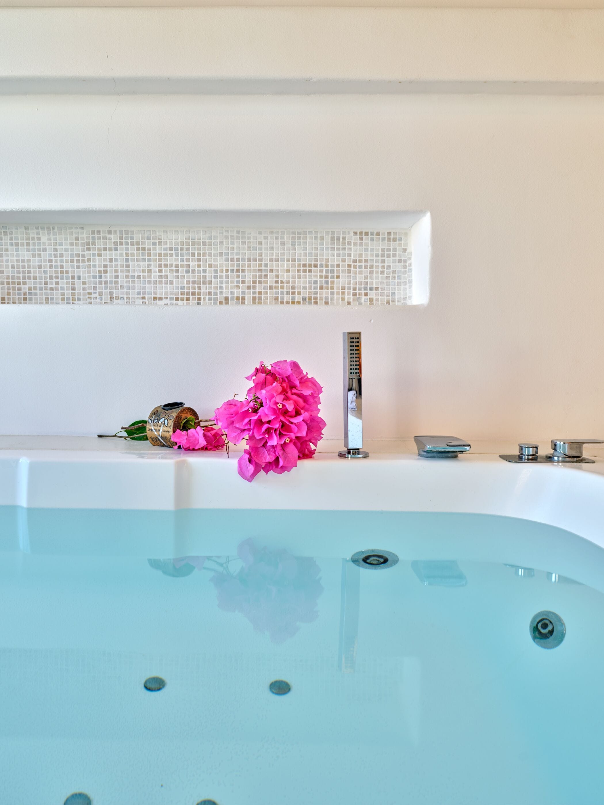 A bathtub with a window above it, a faucet, and a decorative item on the edge.