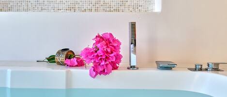 A bathtub with a window above it, a faucet, and a decorative item on the edge.