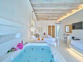 Ett modernt spa-rum med ett stort badkar, en sittgrupp med en soffa och ett skrivbord med en stol.