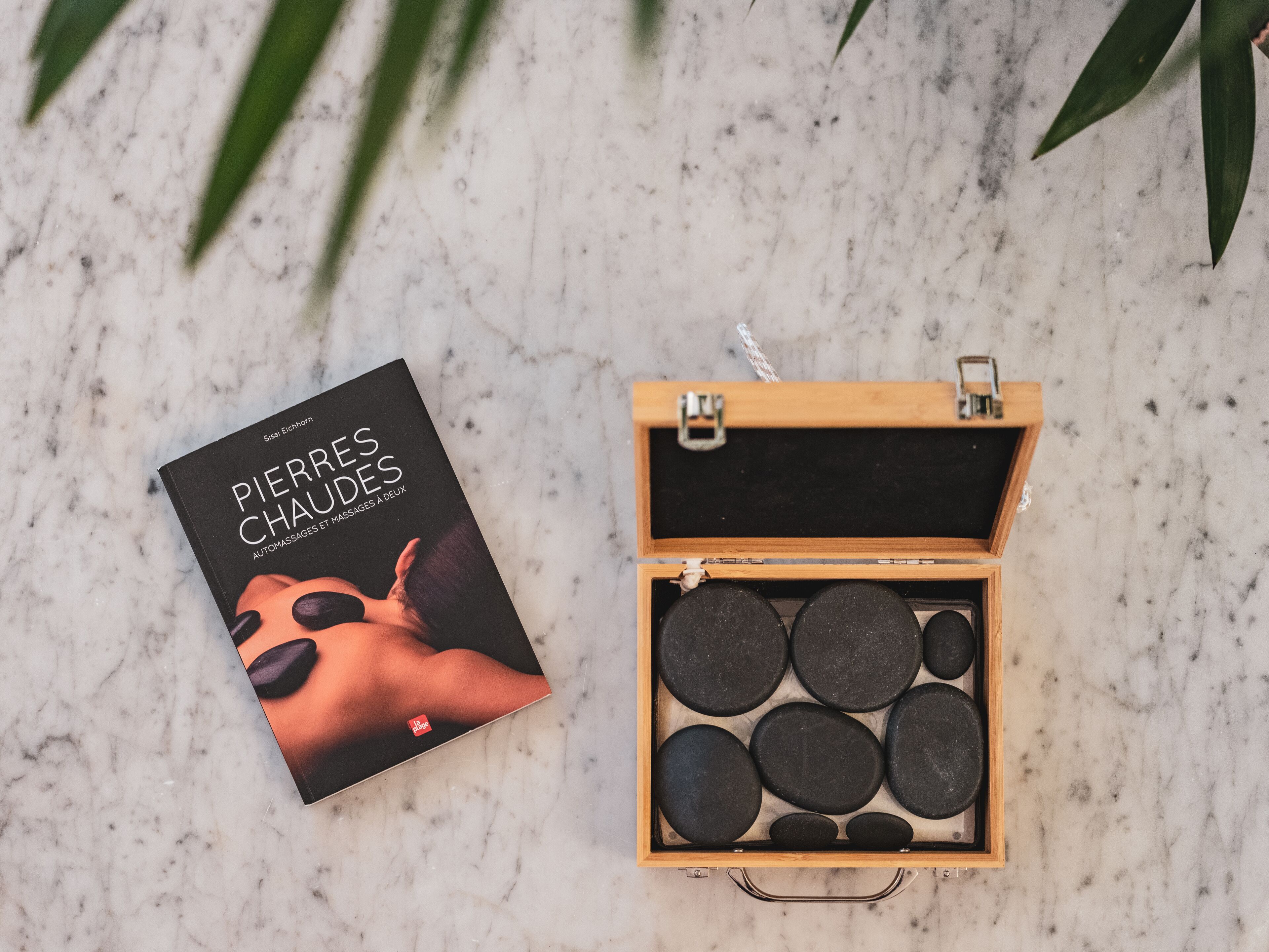 A book titled 'Pierres Chaudes' and a wooden box containing black circular objects.