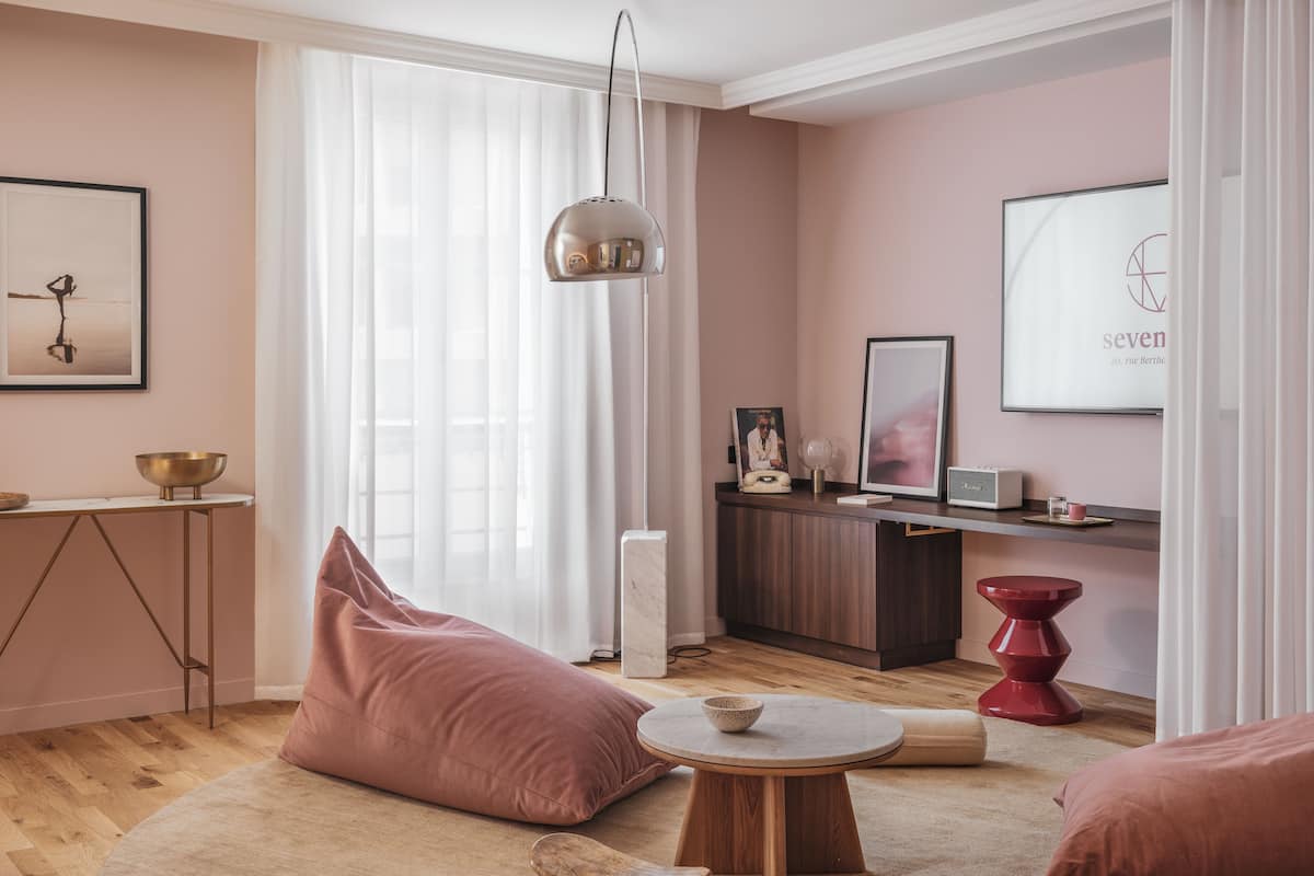 A modern living room with a large window, a round wooden table, and a sofa.
