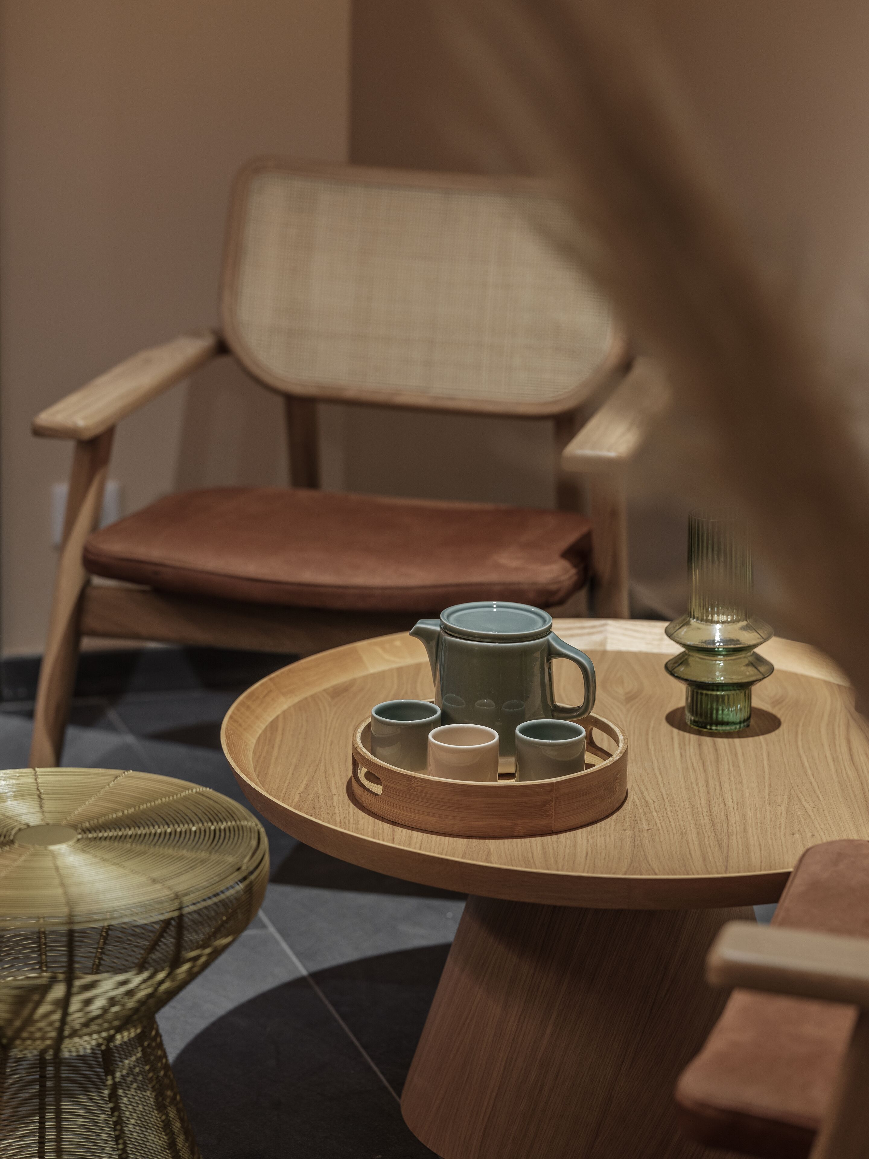 Une table en bois sur laquelle se trouve un plateau avec une théière, des tasses et une bougie.