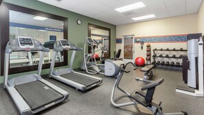 Ein Fitnessstudio mit Laufbändern, Crosstrainern und Kurzhanteln.