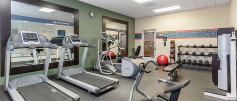 A gym with treadmills, elliptical machines, and free weights.