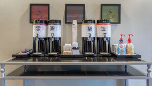 A coffee station with multiple coffee machines, disposable cups, and condiments. - Hampton Inn Richmond - South (Richmond)