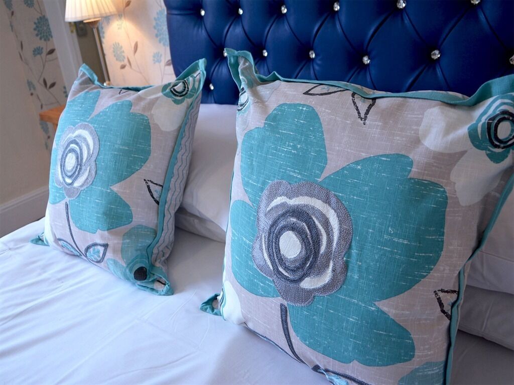A bed with two pillows featuring a floral design.