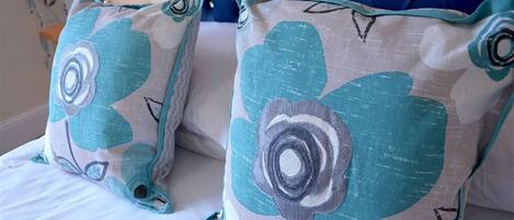 A bed with two pillows featuring a floral design.