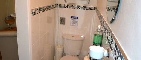A bathroom with a toilet, sink, and a notice sign on the wall.