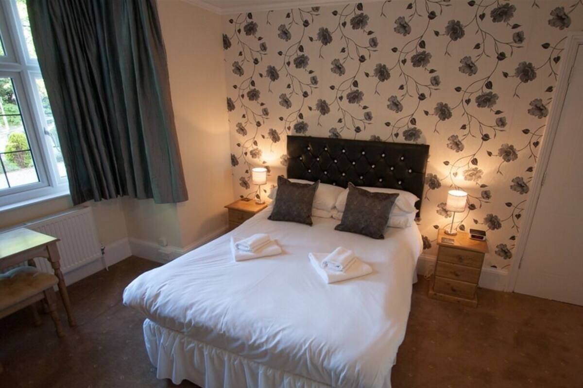 A neatly made bed with pillows and a bedside table with a lamp.