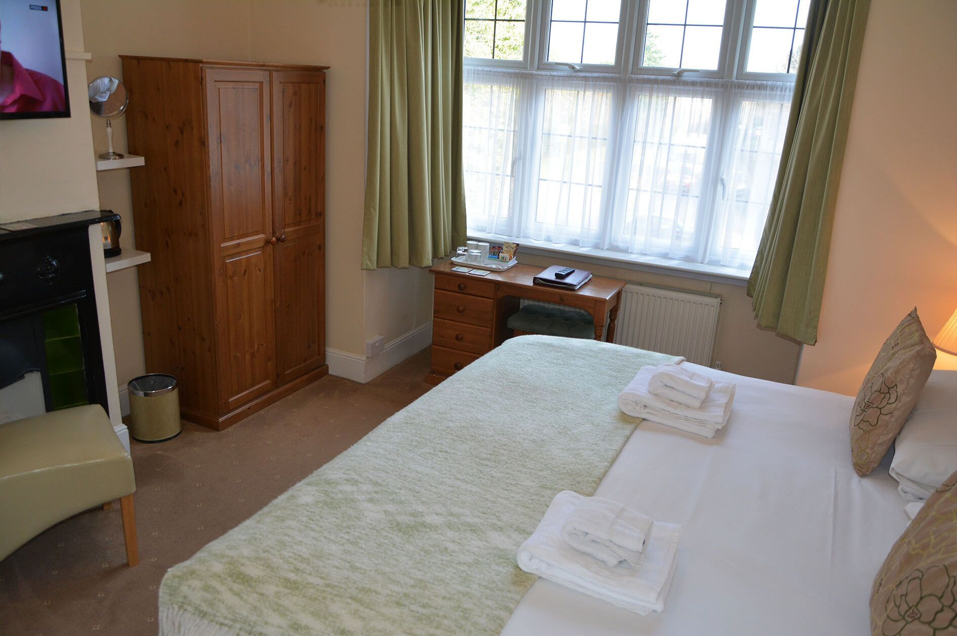 Een slaapkamer met een bed, een bureau, een kledingkast en een radiator.
