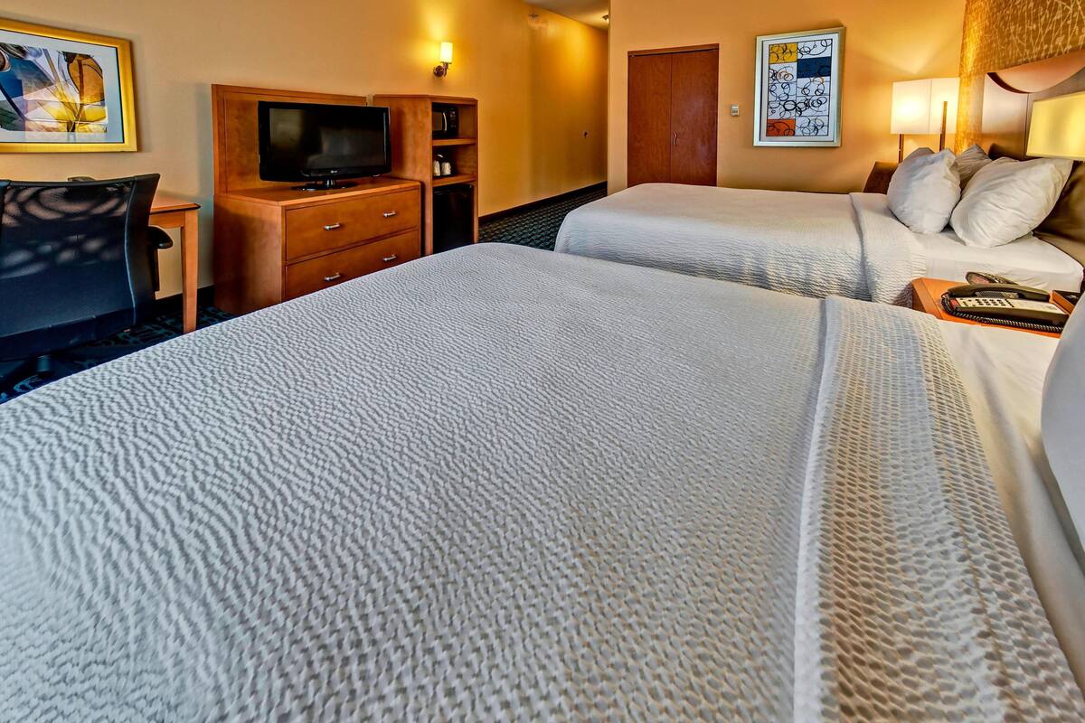 A hotel room with two beds, a TV, a desk, and a wardrobe.