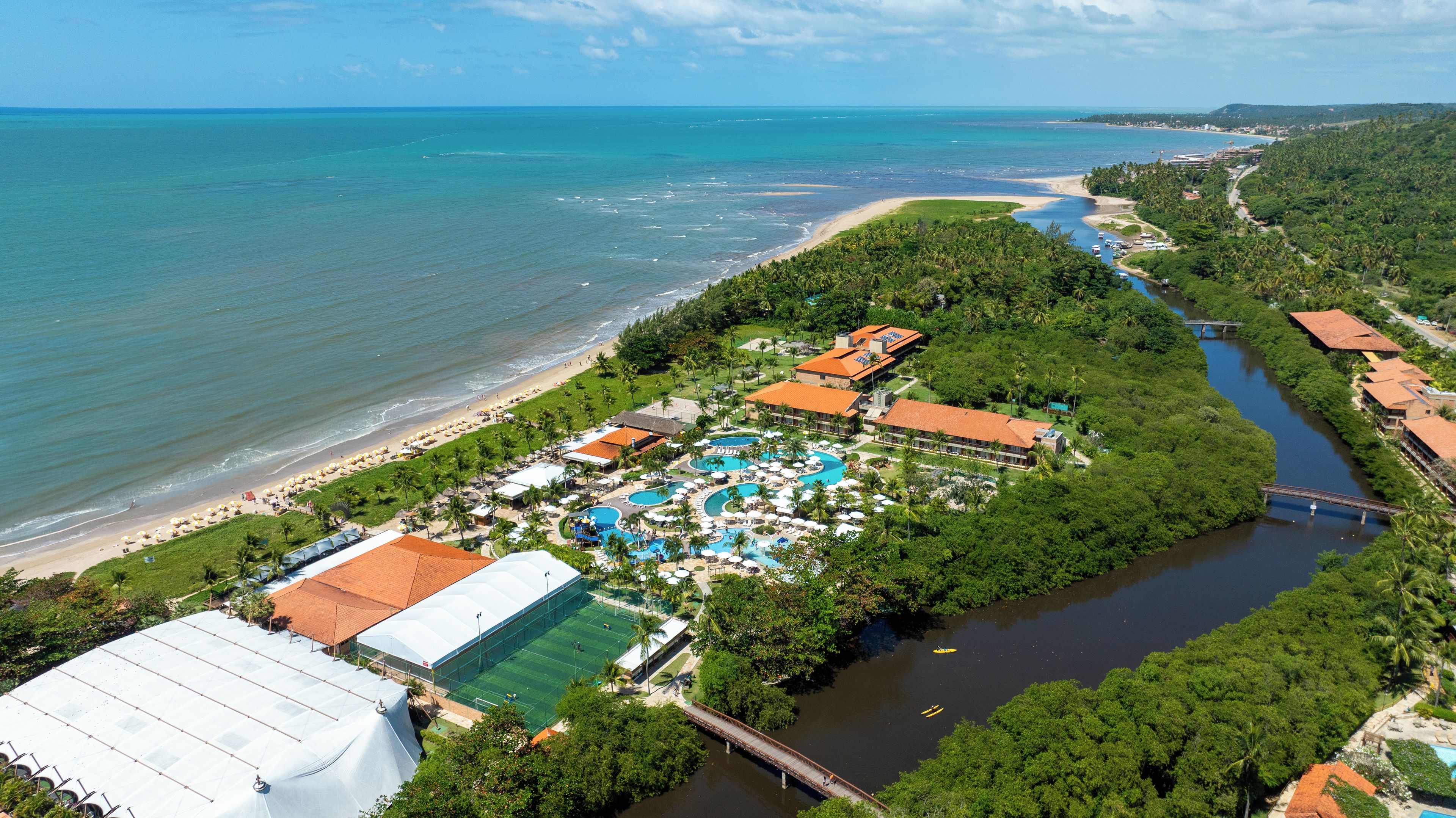 Resort com praia, piscinas e rio.