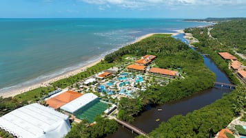 Resort com praia, piscinas e rio.