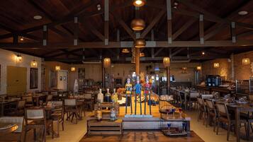 Un restaurante espacioso con vigas de madera, lámparas colgantes y una zona de bar central.