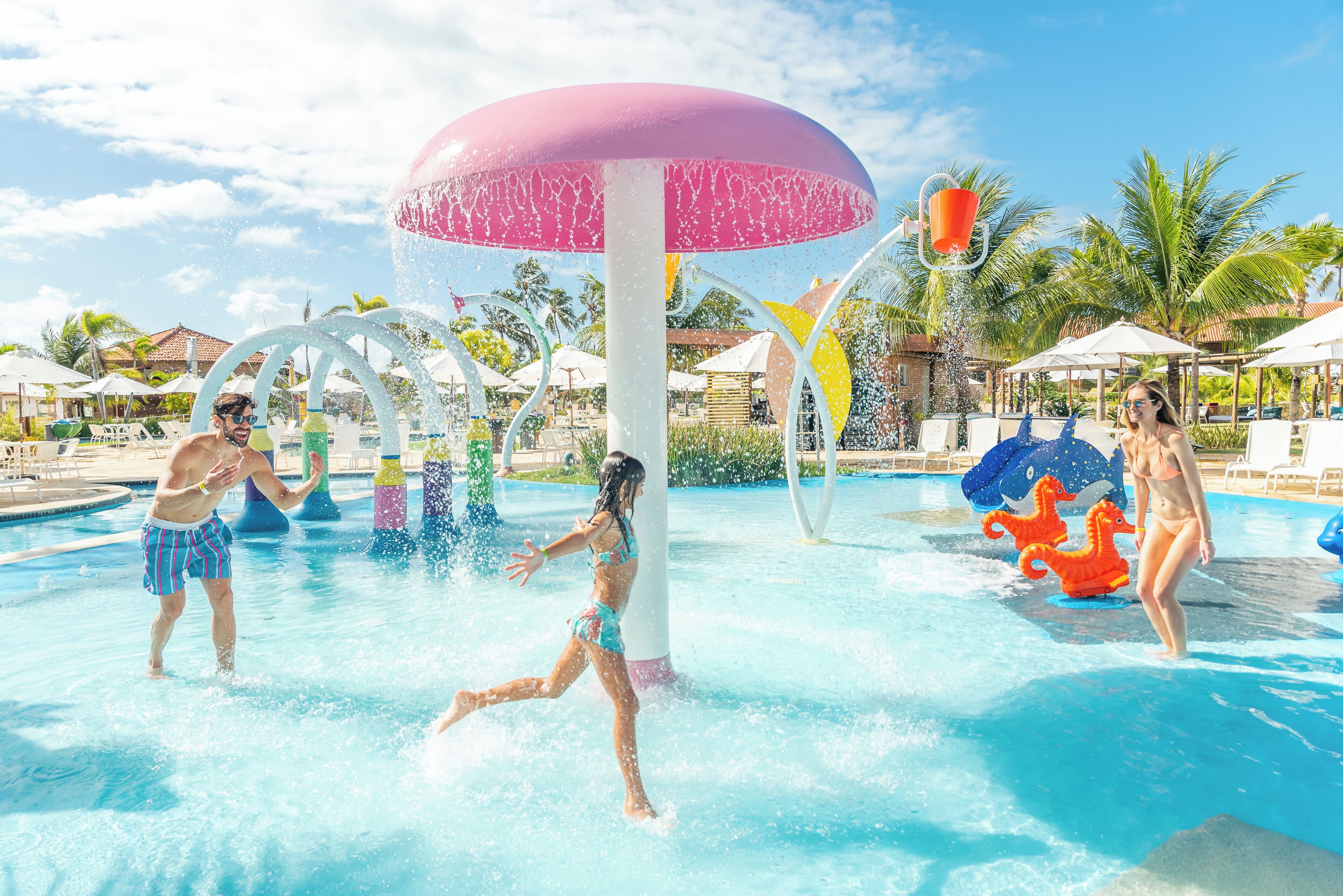 A swimming pool with water features, umbrellas, and lounge chairs.