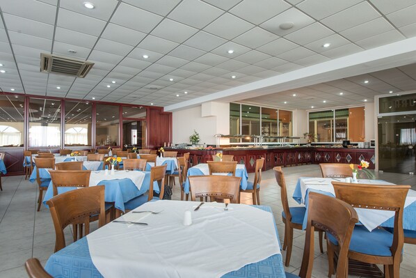 A spacious dining area with multiple tables and chairs, a central bar, and large windows.