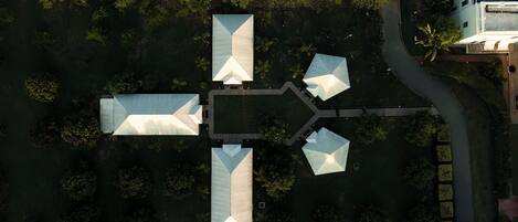 An aerial view of a modern building complex with multiple interconnected structures, surrounded by dense greenery.