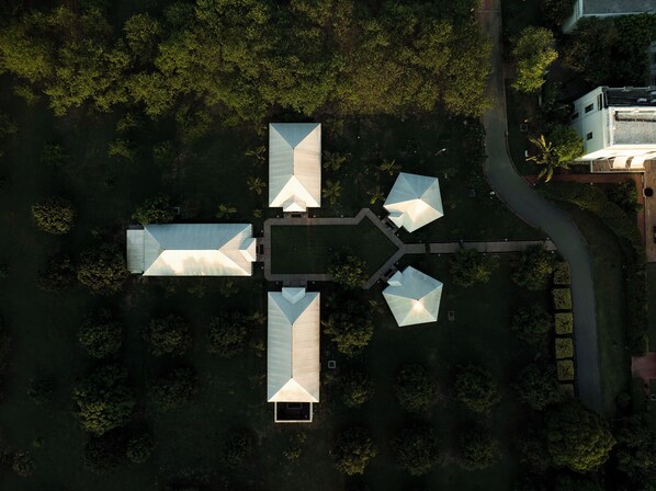 An aerial view of a modern building complex with multiple interconnected structures, surrounded by dense greenery. - Taj Nadesar Palace (Varanasi)