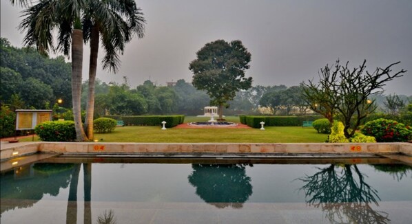 A serene garden with a central fountain, surrounded by well-manicured lawns and palm trees. - Taj Nadesar Palace (Varanasi)