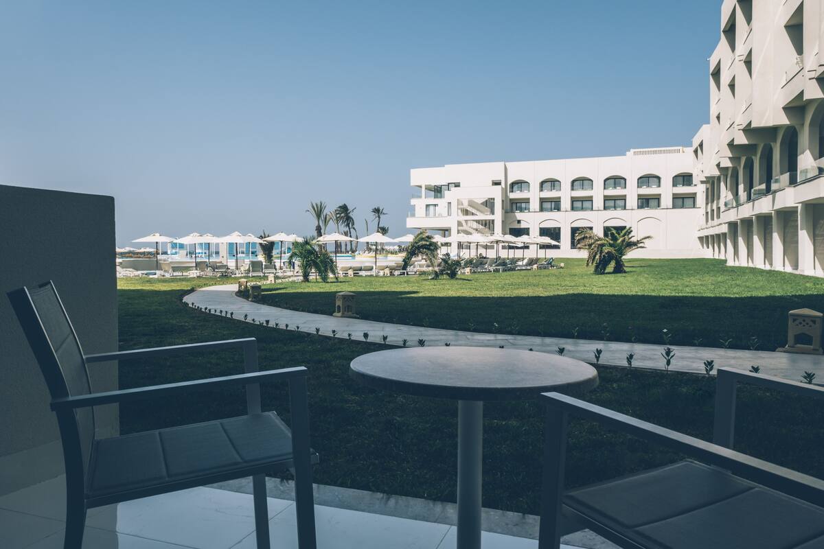 A hotel courtyard with a pool, lounge chairs, and a view of the building.
