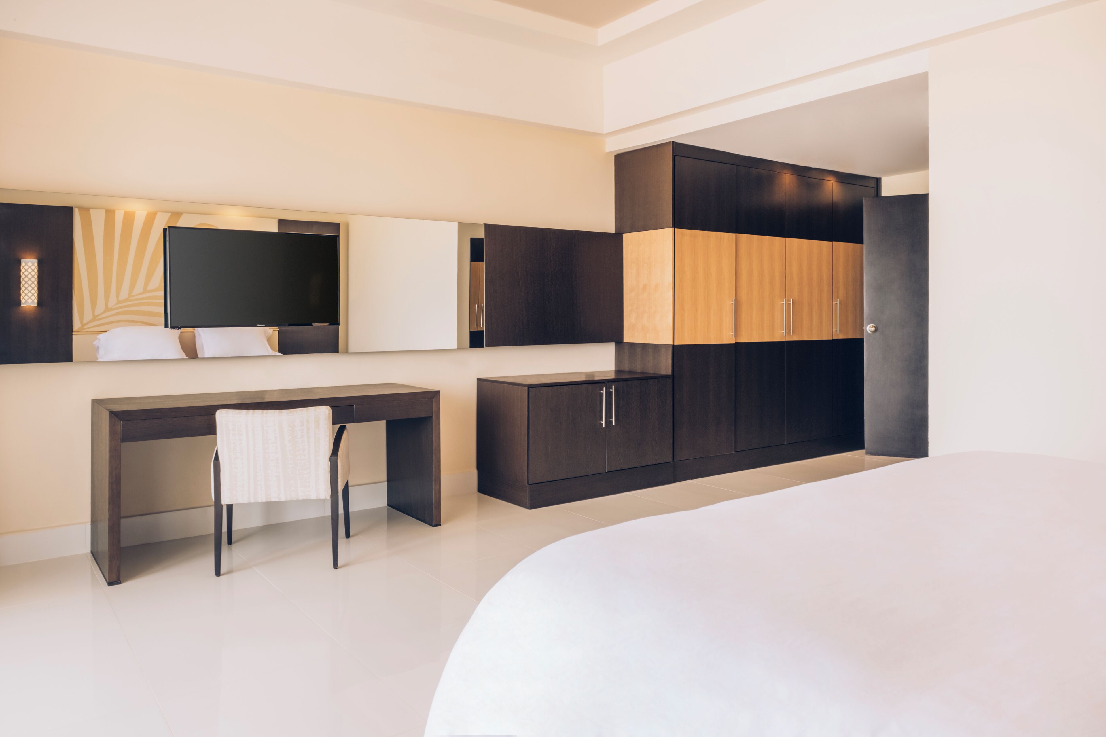 A modern hotel room with a bed, a desk, and a wardrobe.