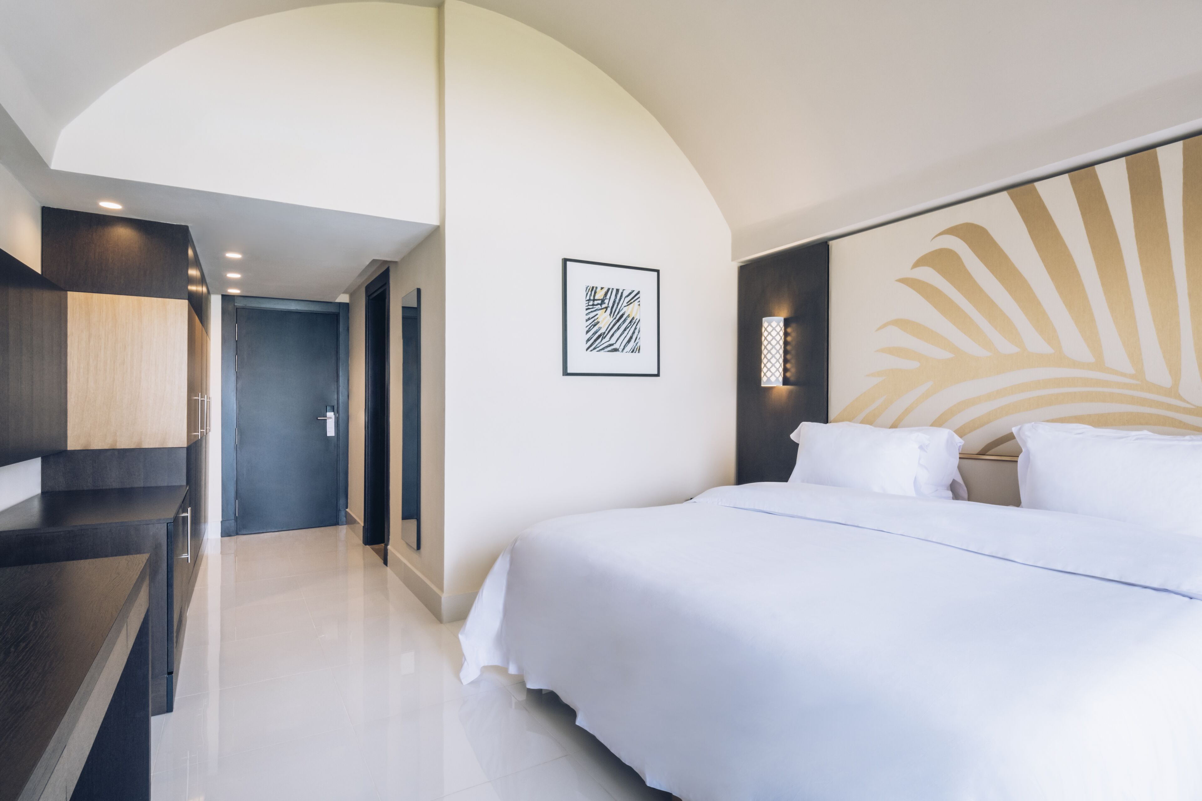 Ein modernes Hotelzimmer mit einem großen Bett, einem Schreibtisch und einem gerahmten Kunstwerk an der Wand.