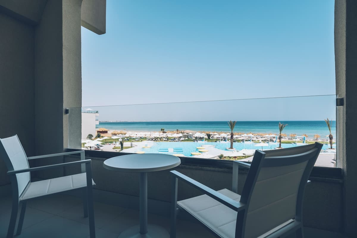 A balcony with a view of a beach and pool area.