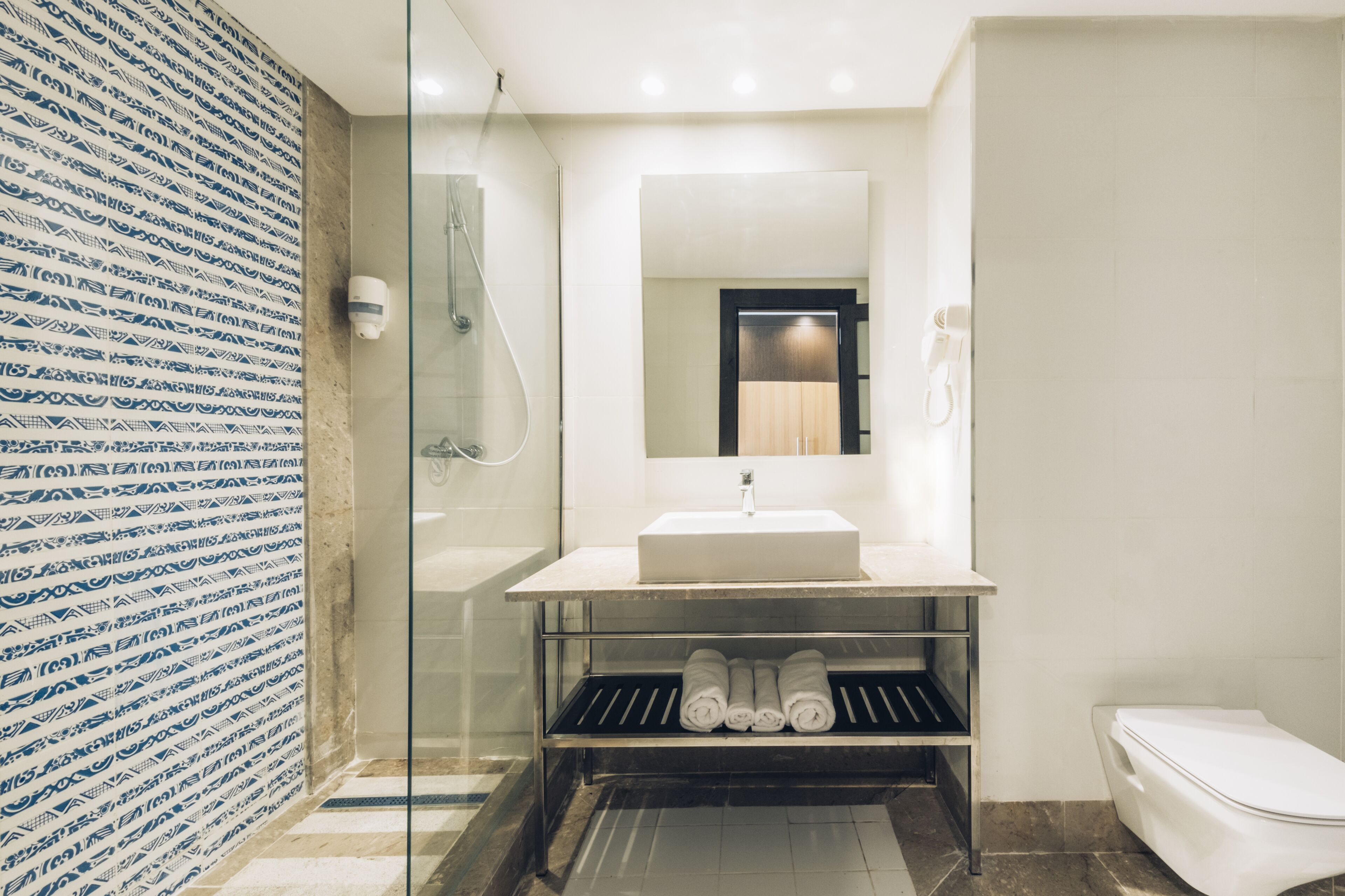 Een moderne badkamer met een douchecabine van glas, een witte wastafel en een toilet.