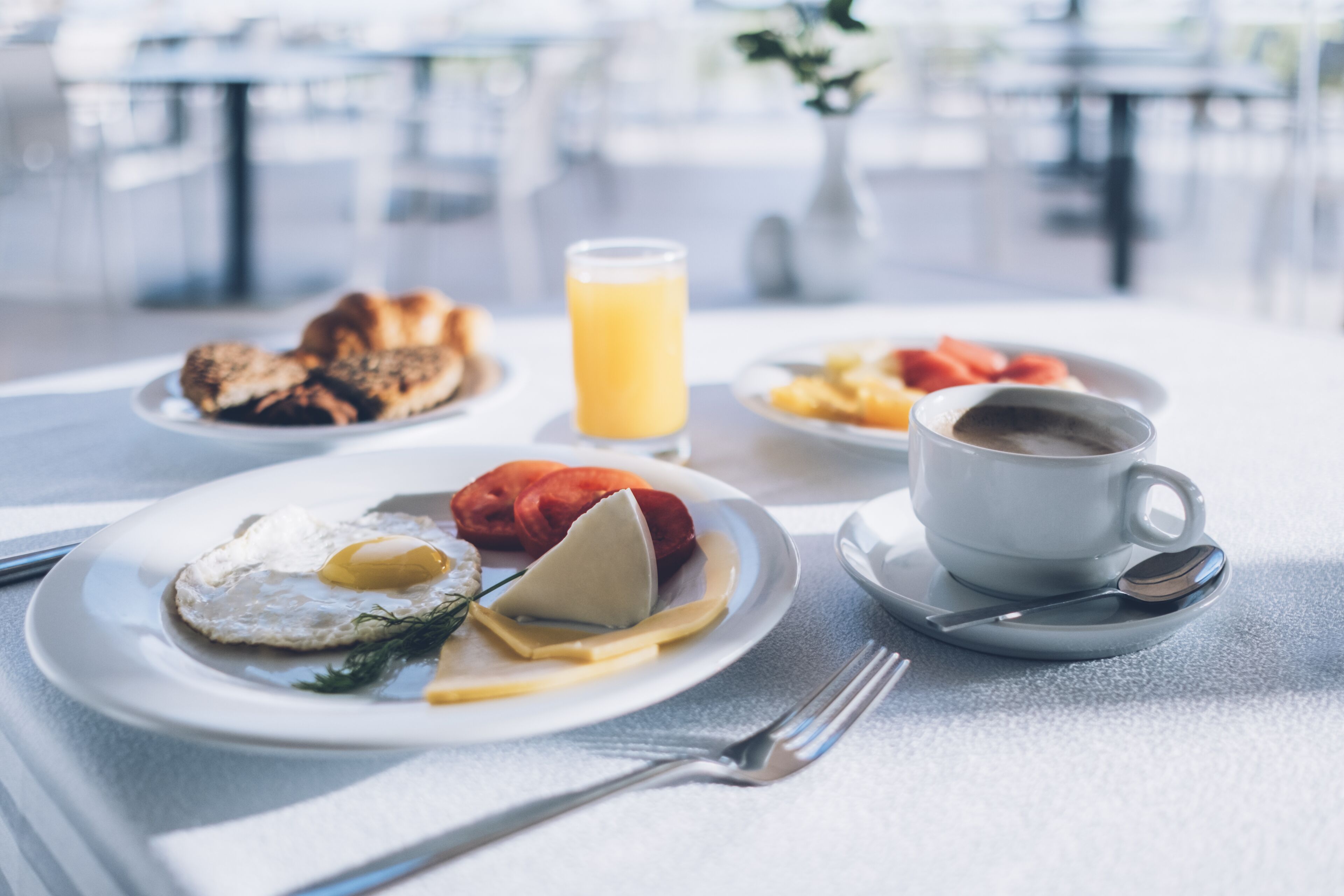 Ein Frühstückstisch mit Speisen, einem Glas Orangensaft und einer Kaffeetasse.