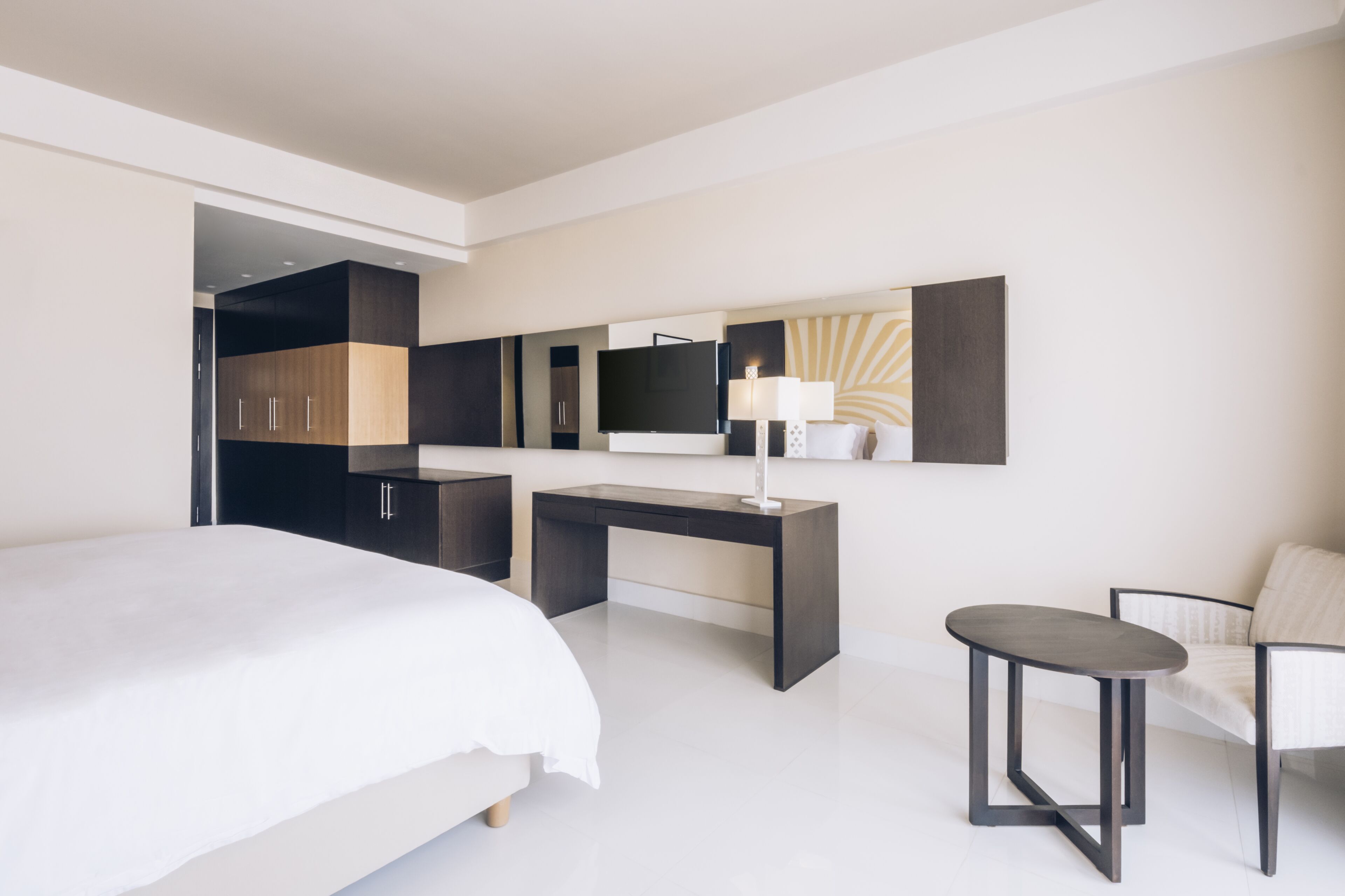 Een moderne hotelkamer met een bed, een bureau, een stoel, een televisie en een lamp.
