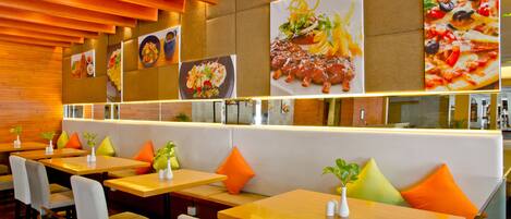 A restaurant with wooden tables and booths, orange cushions, and wall art of food.