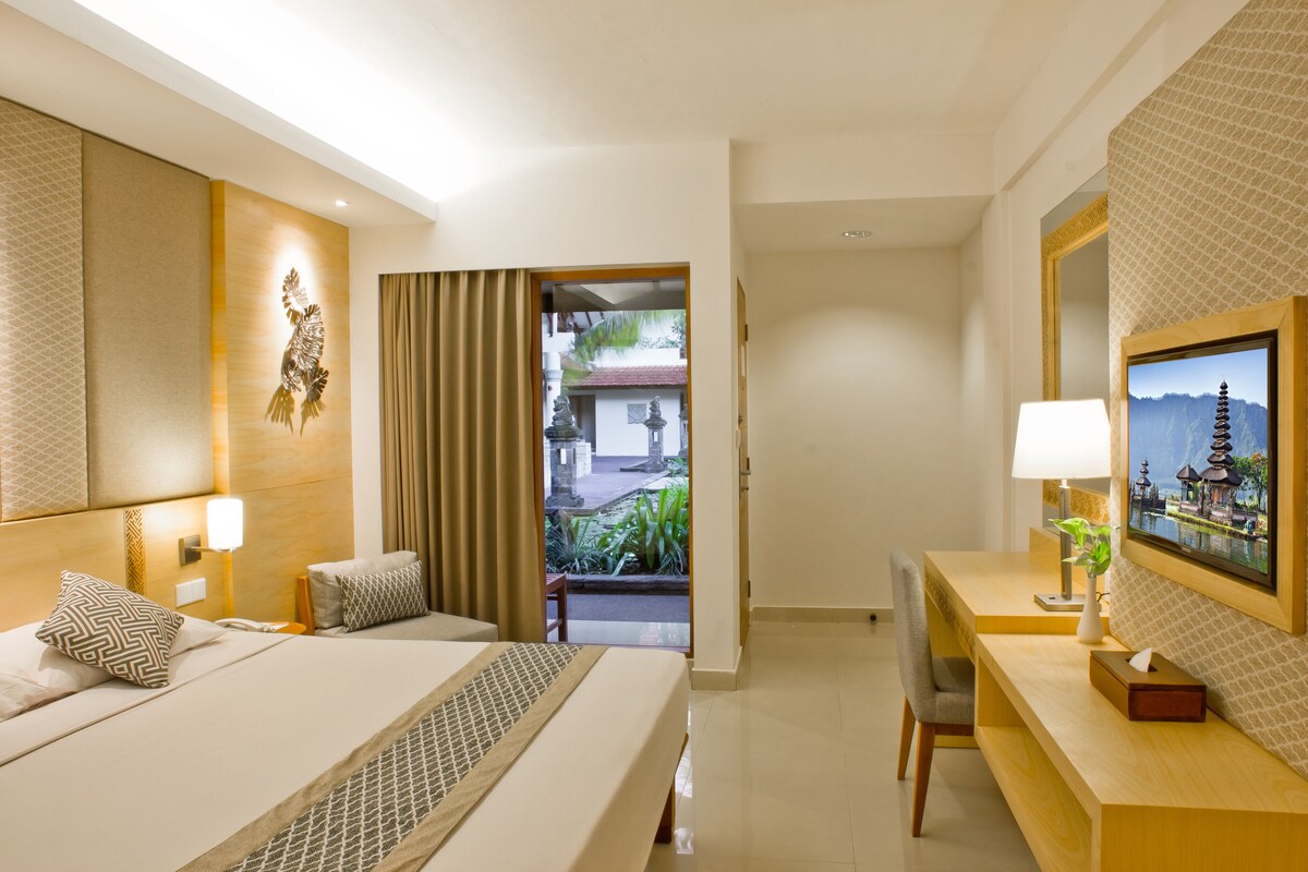 Une chambre d’hôtel comprenant un lit, une table de chevet, une lampe et un bureau avec une chaise.
