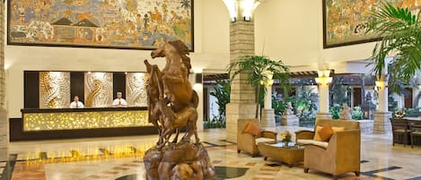 A lobby with a reception desk, a large horse sculpture, and two large wall murals.