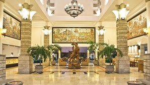 Eine Lobby mit einem zentralen Brunnen, großen Wandgemälden und einer Rezeption.