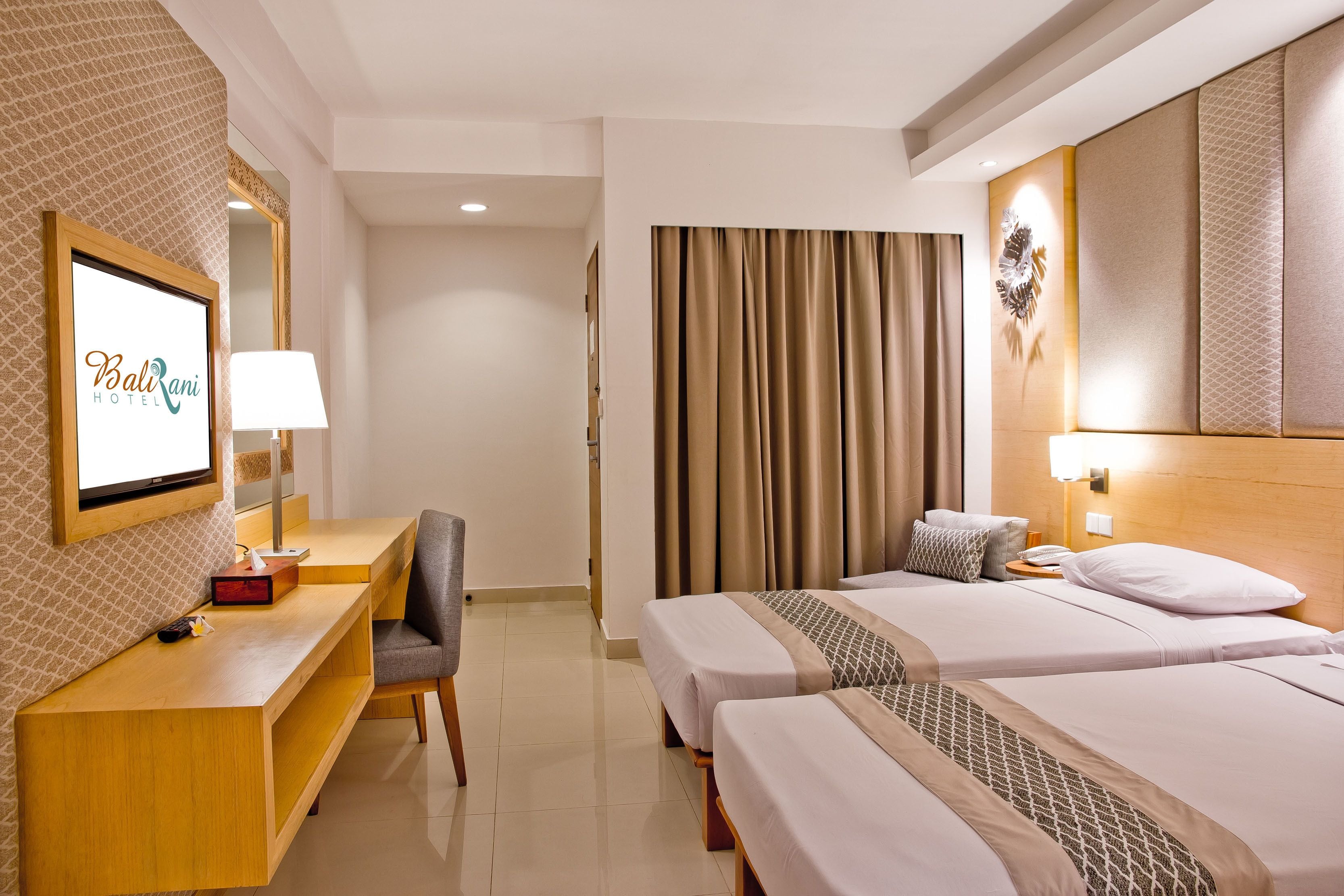 Una habitación de hotel con escritorio, dos camas, espejo y cortina.
