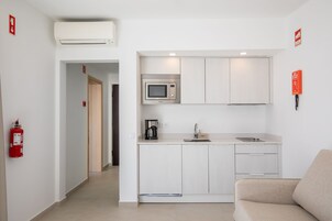 A compact kitchenette with a microwave, coffee maker, and sink.