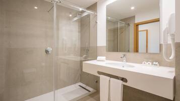 A modern bathroom with a glass-enclosed shower, a white sink, and a large mirror.