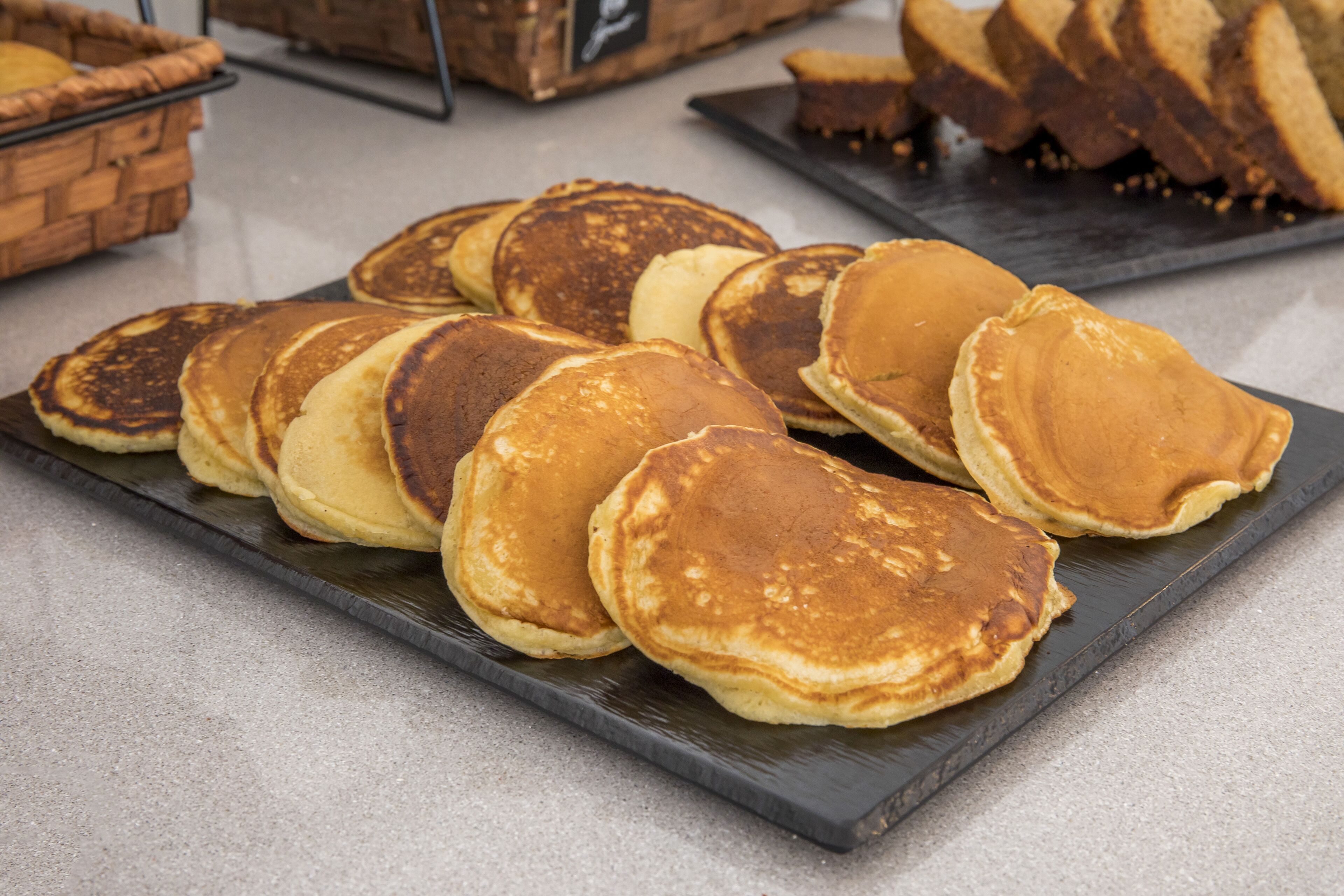 A tray of pancakes on a dark plate.