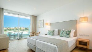 Hotelkamer met een groot bed, een tafeltje, een stoel en uitzicht op een zwembad en gebouwen.