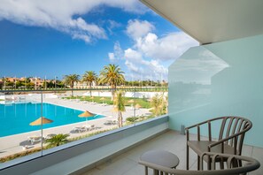 A balcony with a view of a swimming pool, lounge chairs, and palm trees. - Ancora Park (Lagos)